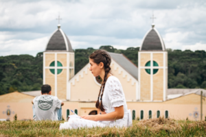 a woman sitting on the ground in front of a church — Foto por Guilherme Gomes Dos Santos na Unsplash