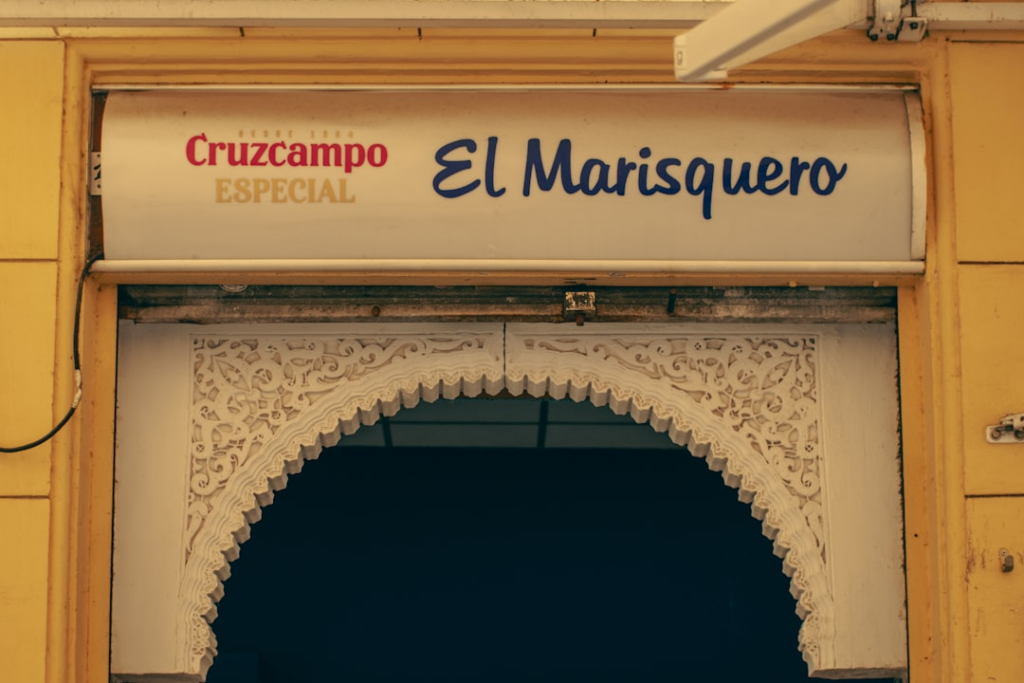 Entrance to el marisquero restaurant with cruzcampo sign — Foto por olga safronova na Unsplash
