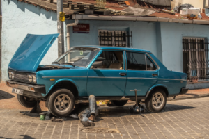 a blue car parked in front of a blue building — Foto por Carlos Torres na Unsplash