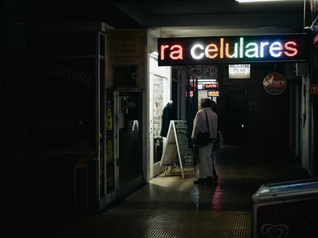 a man walking down a dark hallway next to a neon sign — Foto por Gustavo Alejandro Espinosa Reyes na Unsplash