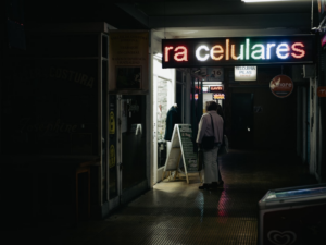 a man walking down a dark hallway next to a neon sign — Foto por Gustavo Alejandro Espinosa Reyes na Unsplash