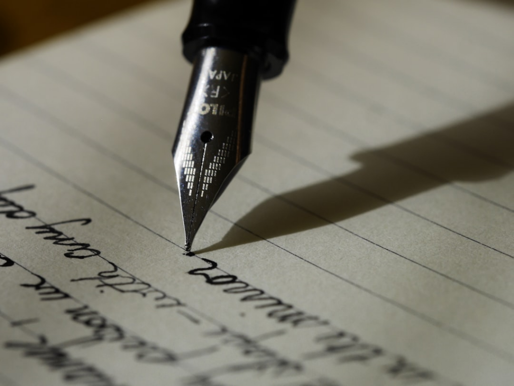 fountain pen on black lined paper — Foto por Aaron Burden na Unsplash