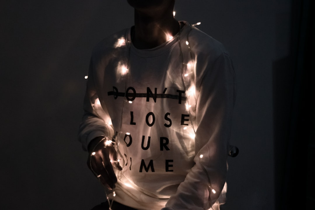 man in white sweater holds lighted Christmas light — Foto por Ali Jouyandeh na Unsplash