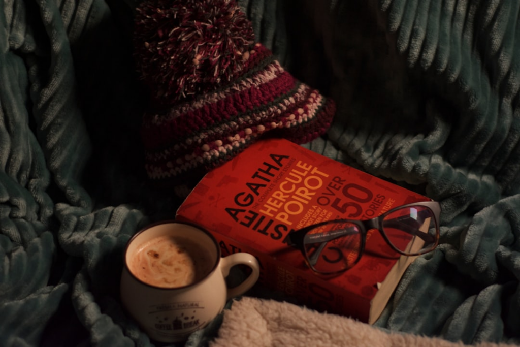 A cup of coffee and a book on a blanket — Foto por Vaibhav Raina na Unsplash