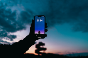 a person holding up a cell phone in front of a cloudy sky — Foto por Omar Ramadan na Unsplash