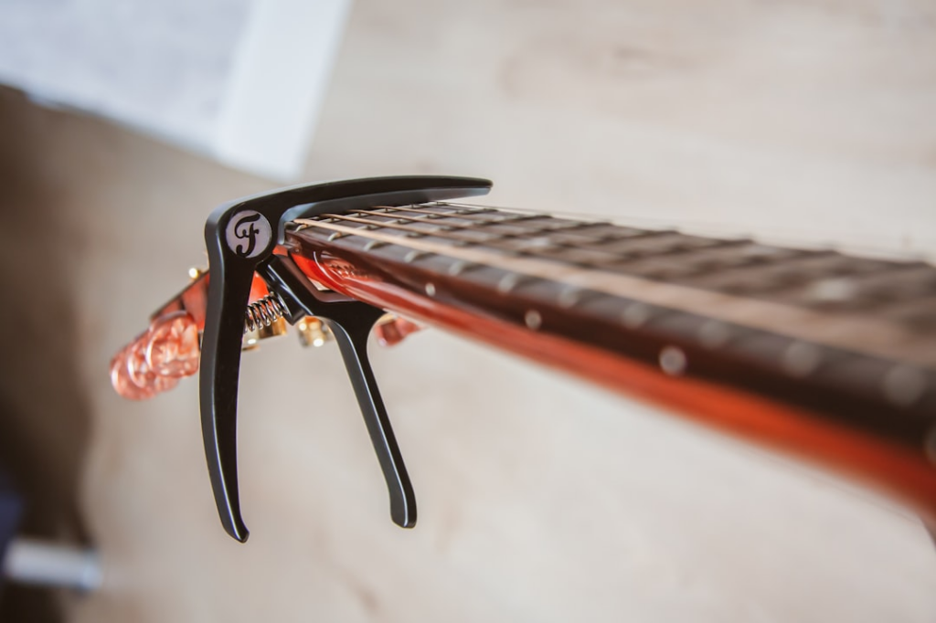 close view of guitar neck with clip — Foto por Ronan na Unsplash