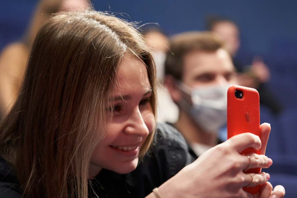woman in black shirt holding red smartphone — Foto por Maxim Tolchinskiy na Unsplash