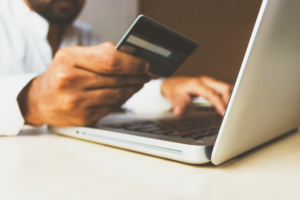 person using laptop computer holding card — Foto por rupixen na Unsplash