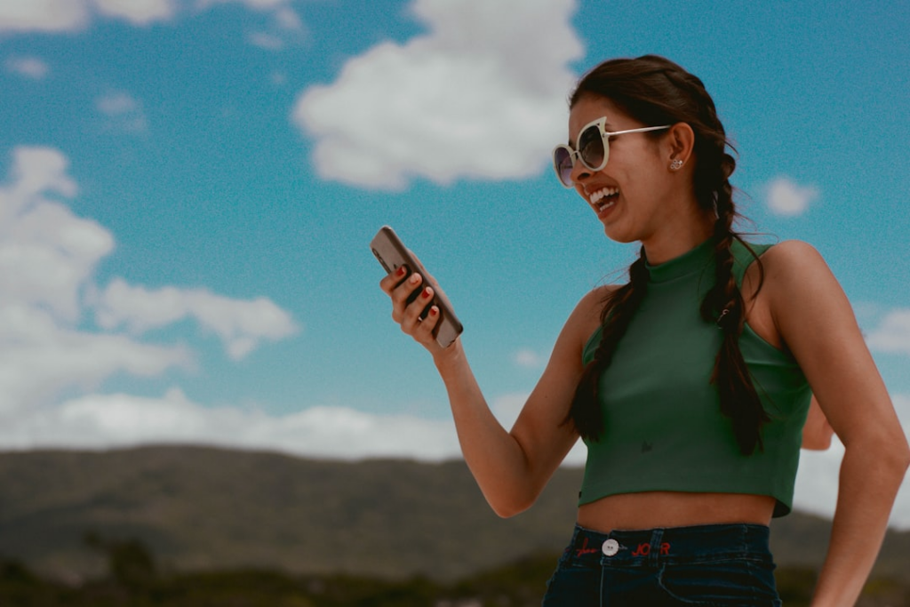 woman in green tank top holding smartphone during daytime — Foto por Carol Magalhães na Unsplash