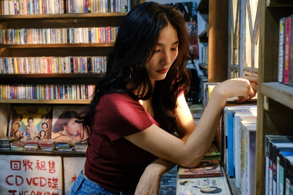 a woman looking through a book shelf in a bookstore — Foto por Frank Ching na Unsplash