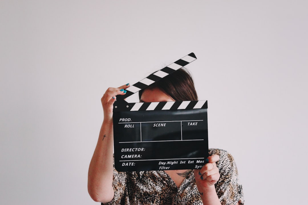 a woman holding a clapper over her face — Foto por Jon Tyson na Unsplash