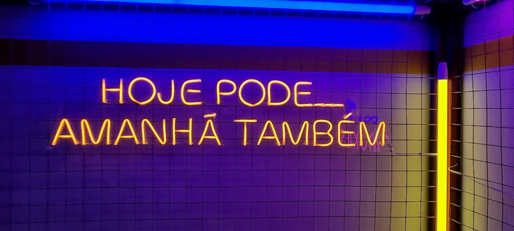 a bathroom with a neon sign above it — Foto por Leonardo Sanches na Unsplash