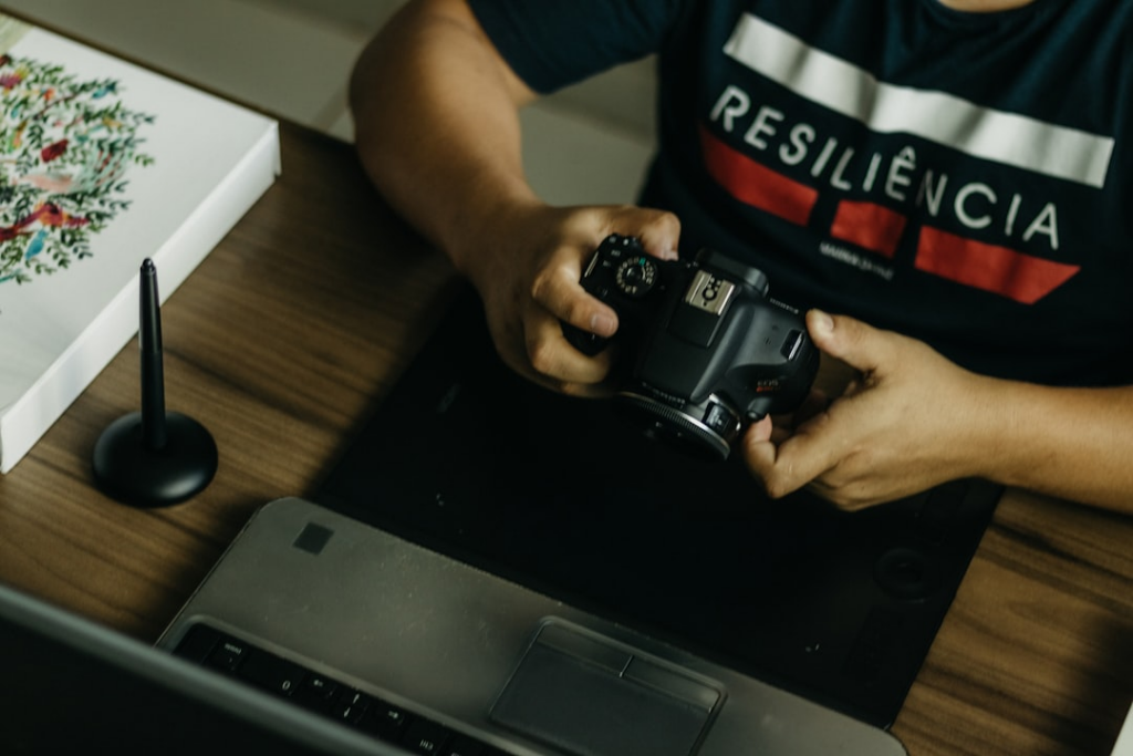 a man sitting at a desk holding a camera — Foto por Kawê Rodrigues na Unsplash