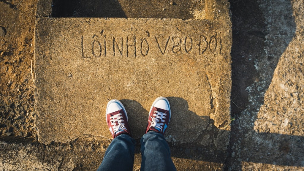 a person standing on a sidewalk with their feet up — Foto por Tien Vu Ngoc na Unsplash