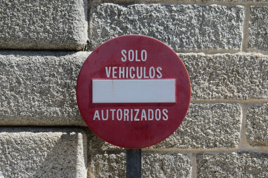Red circular sign "solo vehiculos autorizados" on a stone wall. — Foto por Douglas M. Lugo Aponte na Unsplash