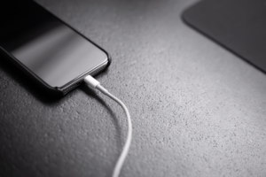 black smartphone with charger cord connected — Foto por Andreas Haslinger na Unsplash