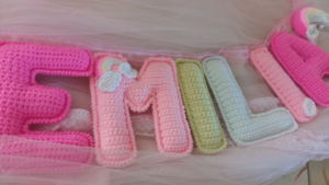 Crocheted letters spelling "emilia" in pink and pastel colors. — Foto por Brenda Ortega na Unsplash