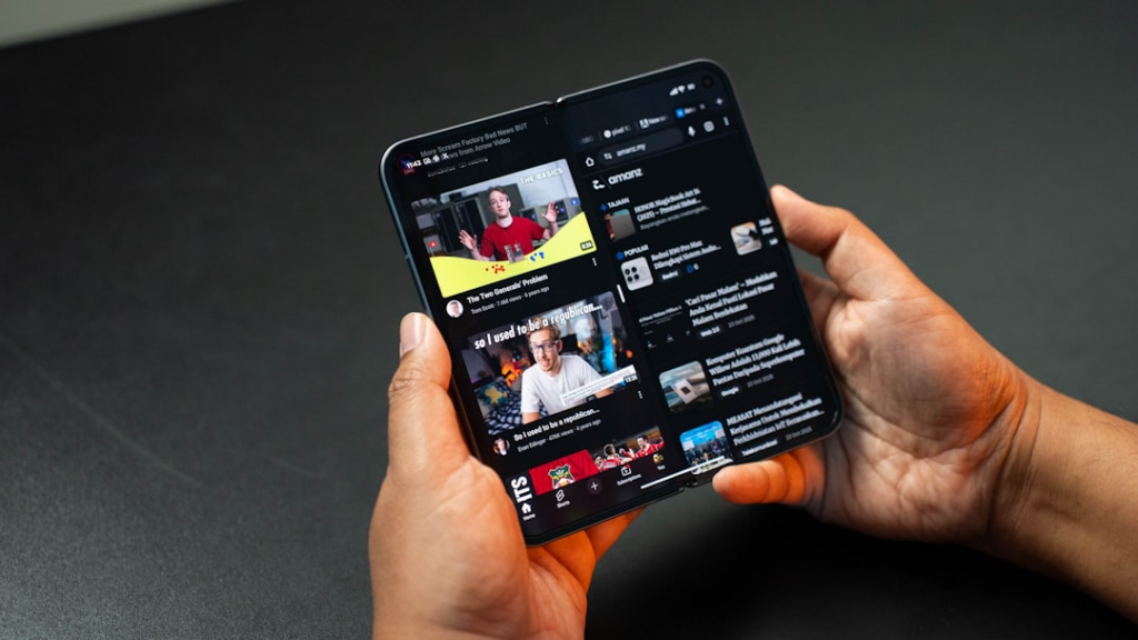 Hands holding a folding smartphone displaying youtube — Foto por Amanz na Unsplash