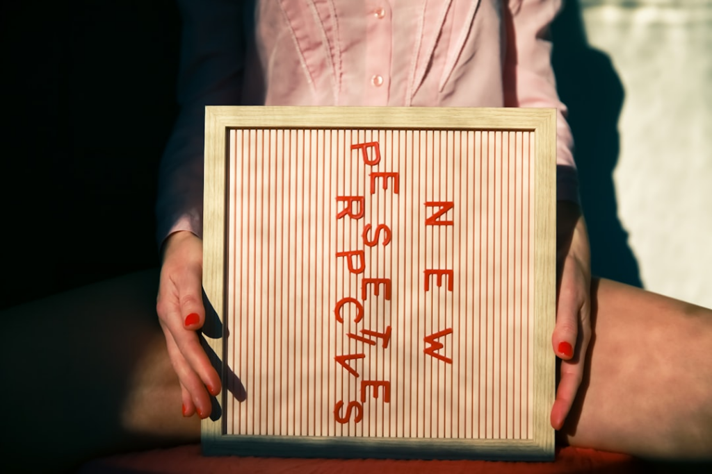 a person holding a sign that says never sustenance — Foto por Ava Sol na Unsplash